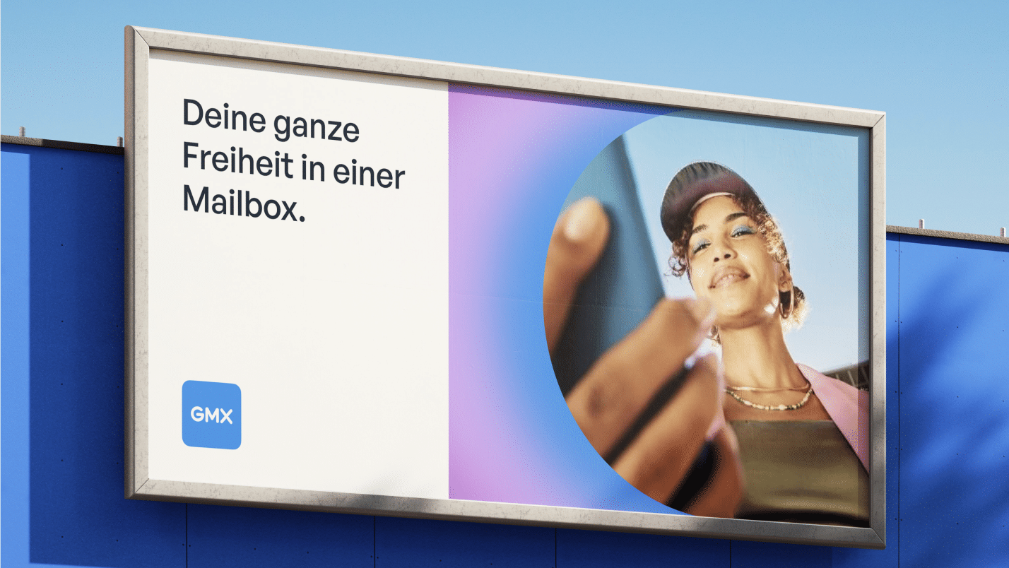 Anwendungsbeispiel für das neue GMX-Design: Plakat mit der Headline „Deine ganze Freiheit in einer Mailbox.“, Frau mit Smartphone und GMX-App-Icon